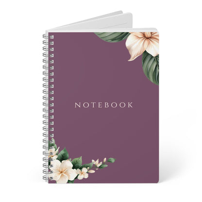 Close-up product photo of the Eternal Light A5 purple spiral notebook featuring white floral corner illustrations. The word NOTEBOOK is printed in white capital letters in the center.