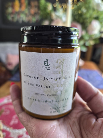 Close-up of Eternal Light candle label on amber glass jar held in hand.