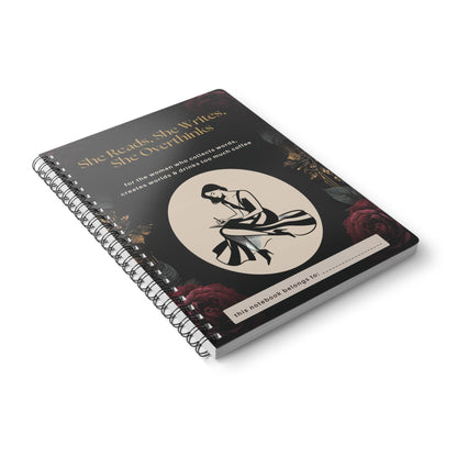 Black and gold spiral notebook for women who love reading and writing, featuring a writer illustration and personalised name space. She Reads, She Writes, She Overthinks journal, lying on blank surface.