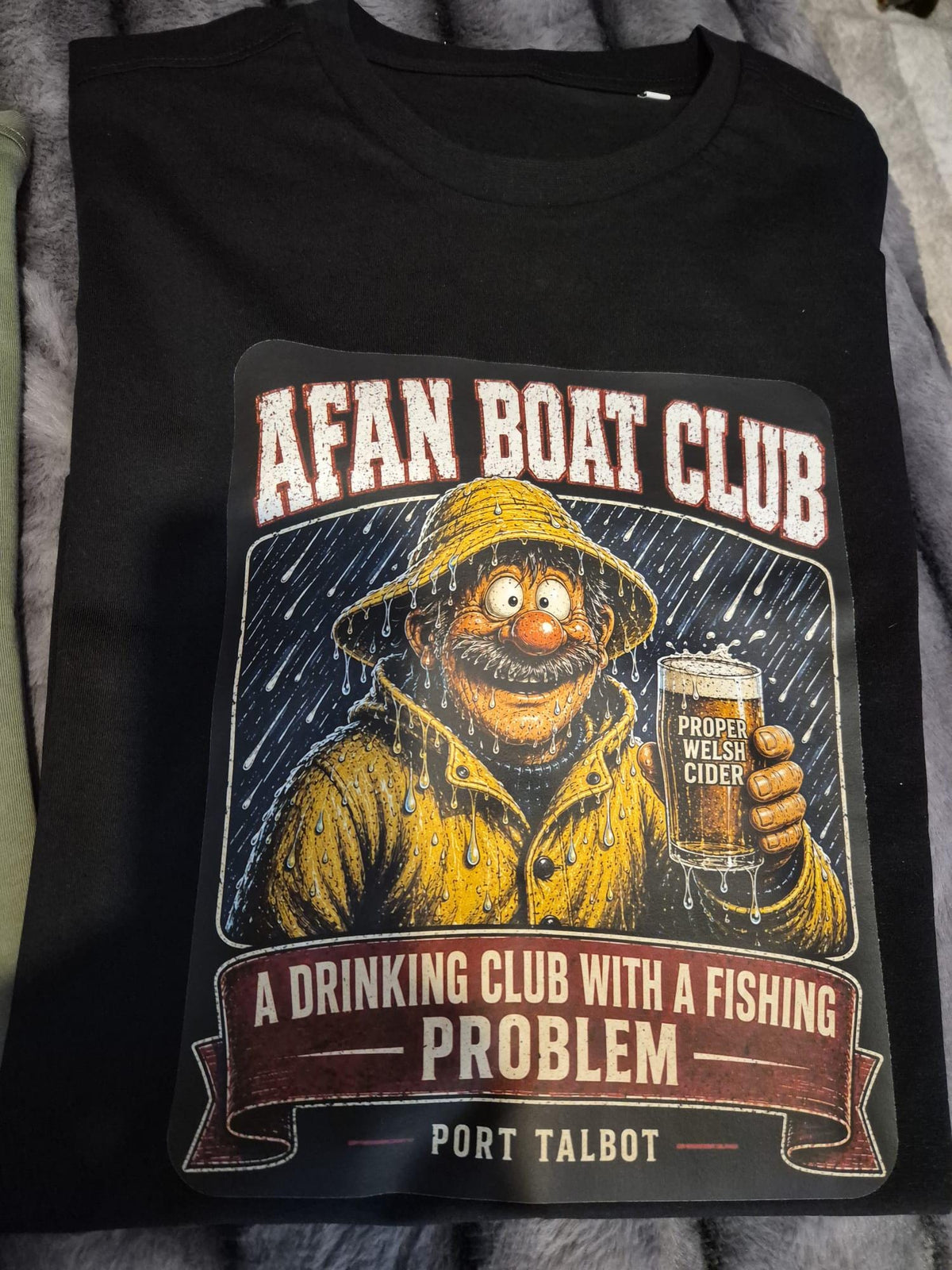 Black Afan Boat Club Fisherman tee, yellow oilskin fisherman holding a pint of Proper Welsh Cider.