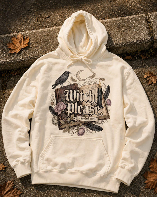 A premium heavyweight hoodie in natural Rice Apricot cream, flat-laid on a kerb. The chest features a hand-drawn dark academia design with gothic text reading "Witch, Please" above a banner that says "a bookish coven." The detailed illustration includes a mystical black raven perched on an open antique book, a burning candle with melting wax, a crescent moon, moths, and delicate purple roses on thorny stems. Perfect aesthetic for spooky book lovers and cozy autumn styles.