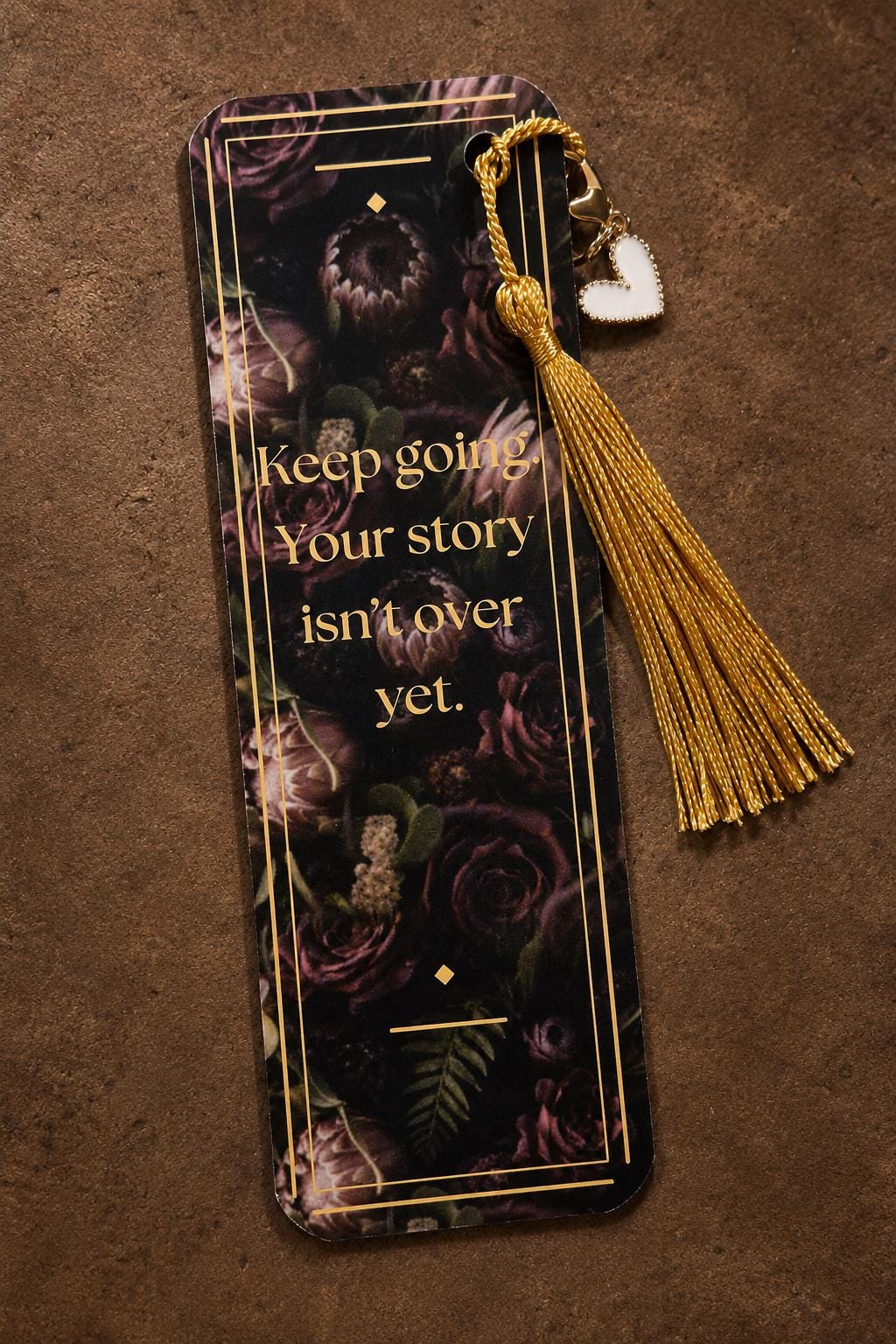Close-up of a custom bookish bookmark featuring a delicate gold tassel and a small heart charm.