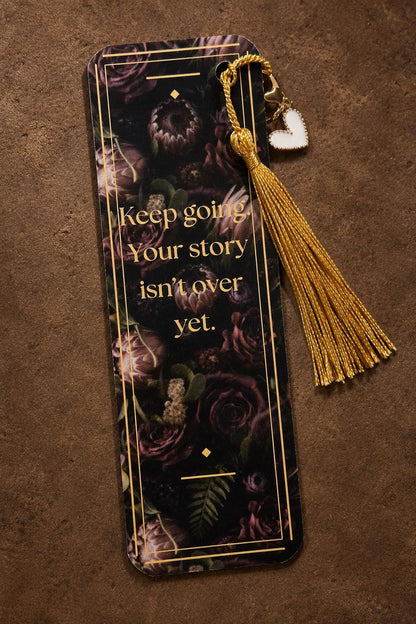 Close-up of a custom bookish bookmark featuring a delicate gold tassel and a small heart charm.