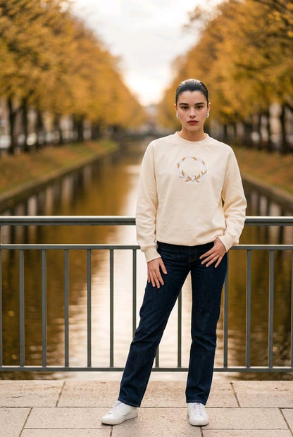 Woman wearing ecru oversized sweatshirt with delicate Lily of the Valley wreath embroidery.